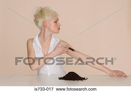 Stock Photo - Young woman injecting coffee into her arm. Fotosearch