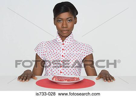 Young woman sat at a table View Large Photo Image Stock Photo - Young woman sat at a table. Fotosearch
