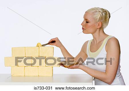 Stock Image - Young woman scraping butter. Fotosearch