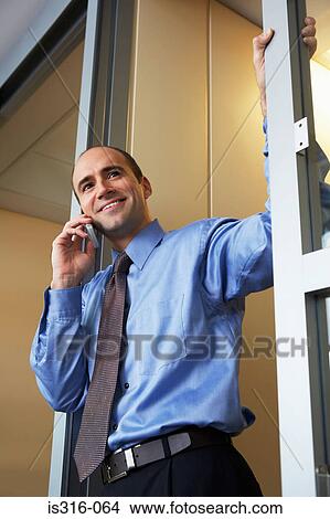 Picture - Businessman using a cellular telephone in doorway. Fotosearch