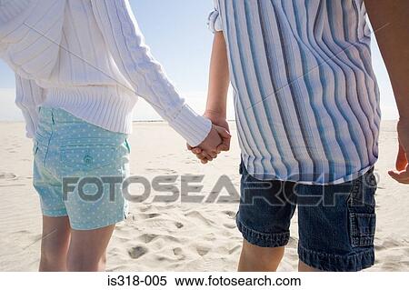 Stock Photography - Boy and girl holding hands on beach. Fotosearch