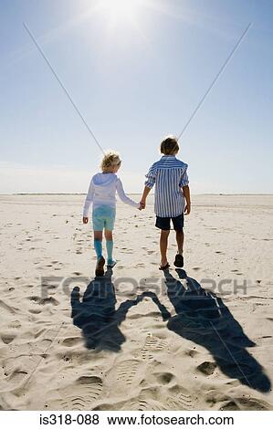 Boy and girl holding hands, walking on beach View Large Photo Image Stock Photo - Boy and girl holding hands, walking on beach. Fotosearch