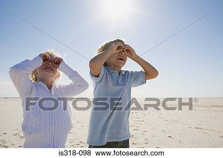 Stock Photo - Boy and girl looking through hands. Fotosearch
