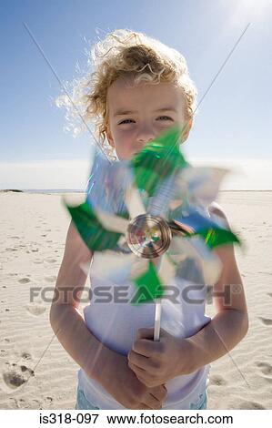 Stock Photo - Girl holding pinwheel on beach. Fotosearch