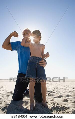 Grandfather and son flexing biceps on beach View Large Photo Image Picture - Grandfather and son flexing biceps on beach. Fotosearch