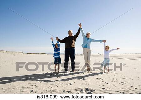 Stock Photo - Grandparents playing with grandchildren on beach. Fotosearch