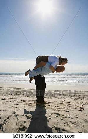 Stock Image - Senior man carrying woman on back. Fotosearch
