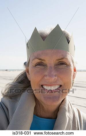 Stock Image - Senior woman wearing paper crown. Fotosearch