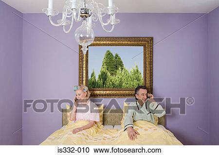 Stock Image - Couple in bed with cellphones. Fotosearch