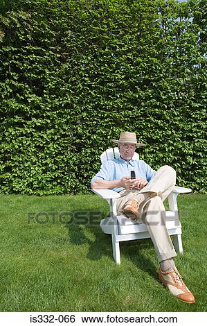 Stock Photograph - Senior man in garden with cellphone. Fotosearch