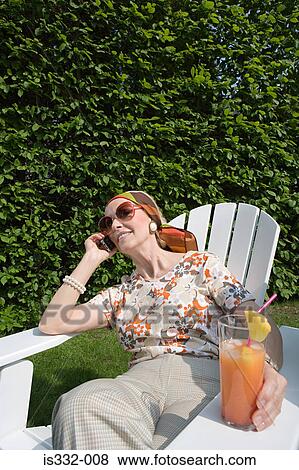 Stock Photo - Senior woman on cellphone in garden. Fotosearch