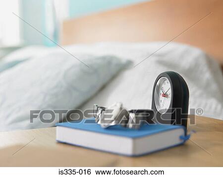 Stock Photograph - Clock and book on a bedside table. Fotosearch