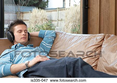 Stock Photo - Man listening to music on sofa. Fotosearch