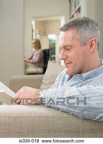 Stock Photo - Mature man reading on sofa. Fotosearch