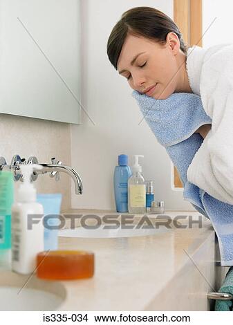 Woman drying her face in bathroom View Large Photo Image Picture - Woman drying her face in bathroom. Fotosearch