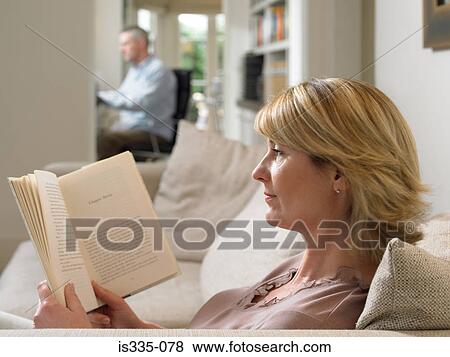 Stock Photo - Woman reading a book on sofa. Fotosearch