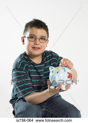 Picture - Boy putting coin in piggy bank. Fotosearch