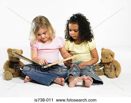 Girls looking at a picture book View Large Photo Image Stock Image - Girls looking at a picture book. Fotosearch