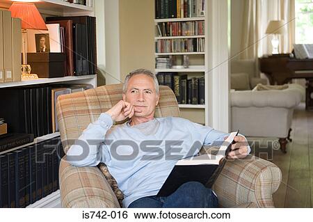 Man in an arm chair with book View Large Photo Image Stock Photograph - Man in an arm chair with book. Fotosearch