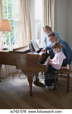 Stock Photograph - Parents with daughter playing piano. Fotosearch