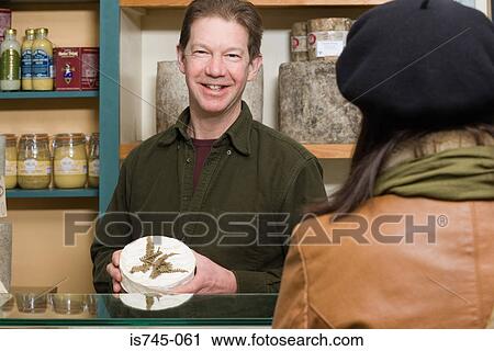 Stock Image - Cheesemonger serving a customer. Fotosearch