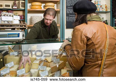 Stock Photo - Cheesemonger serving a customer. Fotosearch