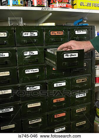 Stock Photograph - Man opening draw in hardware shop. Fotosearch