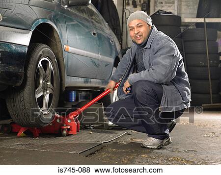 Stock Photo - Mechanic using trolley jack. Fotosearch