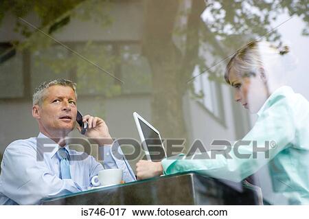 Stock Photo - Business couple working at bar table, view through window. Fotosearch