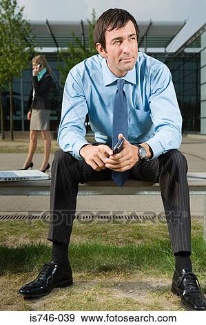 Stock Photo - Businessman sitting on bench outdoors. Fotosearch