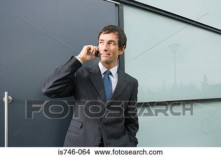 Picture - Businessman talking on mobile phone outdoors. Fotosearch