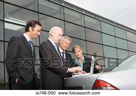 Businesspeople looking at laptop on automobile boot View Large Photo Image Stock Image - Businesspeople looking at laptop on automobile boot. Fotosearch