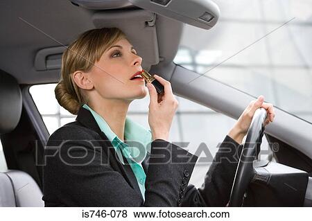 Businesswoman applying lipstick in car View Large Photo Image Stock Photo - Businesswoman applying lipstick in car. Fotosearch
