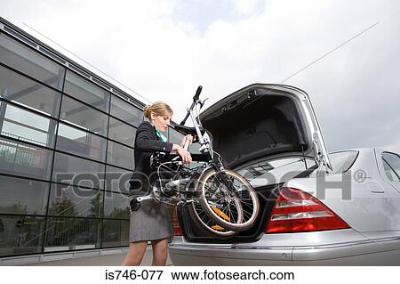 Businesswoman putting folded bicycle in car boot View Large Photo Image Stock Photo - Businesswoman putting folded bicycle in car boot. Fotosearch
