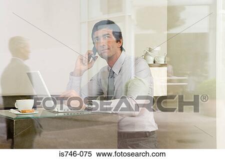 Stock Photography - Man with laptop in coffee bar, View through window). Fotosearch