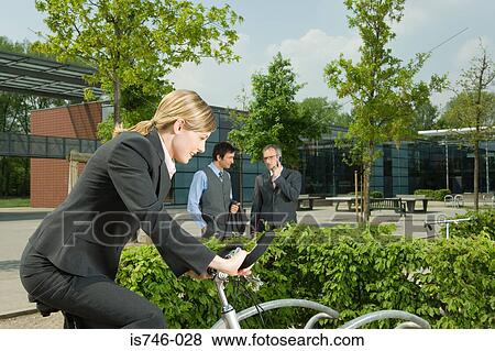 Woman on bike, two businessmen on background View Large Photo Image Stock Photo - Woman on bike, two businessmen on background. Fotosearch