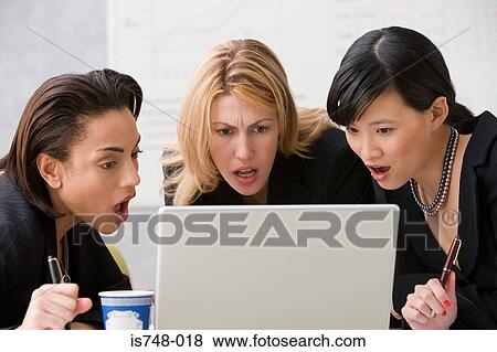 Three young women looking shocked at opened laptop View Large Photo Image Stock Photo - Three young women looking shocked at opened laptop. Fotosearch