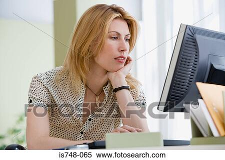 Stock Photography - Young woman working at desk. Fotosearch