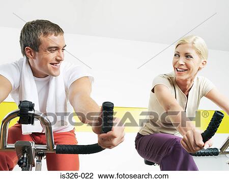 Man and woman exercising cycling in health club View Large Photo Image Stock Image - Man and woman exercising cycling in health club. Fotosearch