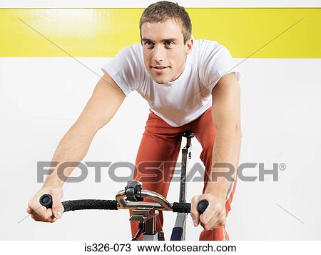 Stock Image - Man on exercise bike in health club. Fotosearch