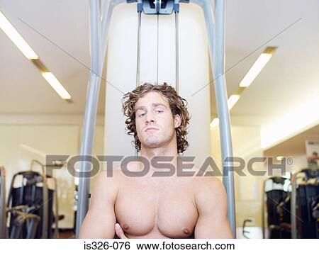 Man sitting at exercising equipment View Large Photo Image Stock Photograph - Man sitting at exercising equipment . Fotosearch