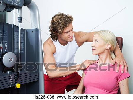 Personal trainer assisting woman at weight machine in gym View Large Photo Image Stock Photo - Personal trainer assisting woman at weight machine in gym. Fotosearch