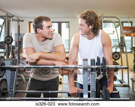 Two men standing at exercising equipment View Large Photo Image Stock Image - Two men standing at exercising equipment. Fotosearch