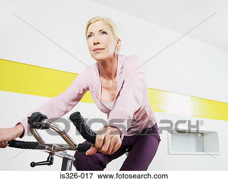 Woman exercising cycling in health club View Large Photo Image Stock Photo - Woman exercising cycling in health club . Fotosearch