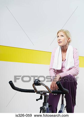 Woman on exercise bike in health club View Large Photo Image Stock Photo - Woman on exercise bike in health club. Fotosearch
