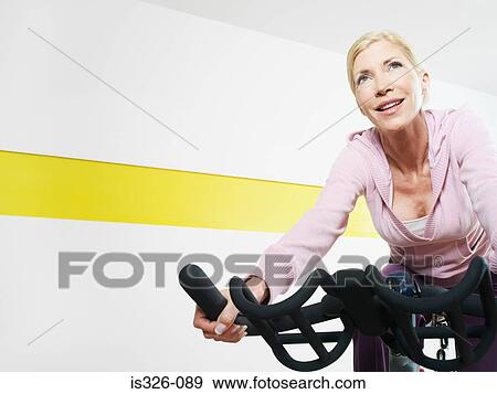 Stock Photo - Woman on exercise bike in health club . Fotosearch