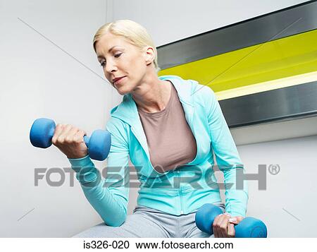 Stock Image - Woman weightlifting in health club. Fotosearch