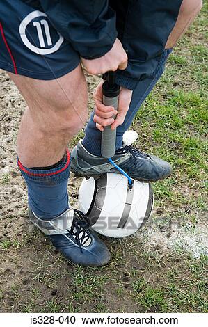 Stock Image - Footballer pumping up football. Fotosearch