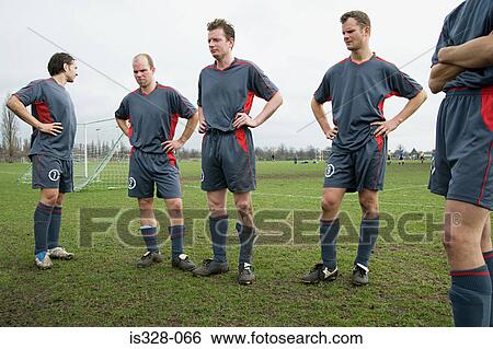 Stock Photograph - Footballers standing on the pitch. Fotosearch