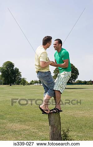 Gay couple balancing on a tree stump View Large Photo Image Stock Photo - Gay couple balancing on a tree stump. Fotosearch